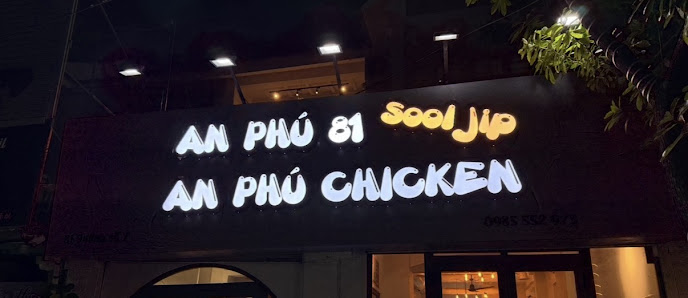 The image depicts the exterior signage of a restaurant named 'AN PHÚ 81 SooJip AN PHÚ CHICKEN' at night. The sign features illuminated text with 'AN P