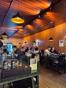 The image depicts the interior of a restaurant in Thao Dien, Saigon. It features wooden walls and ceiling with warm-toned lighting from hanging pendan