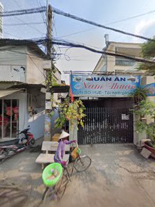 The image depicts the exterior of a venue in Thao Dien, Saigon. A person wearing a conical hat and purple shirt is riding a bicycle with a green circu
