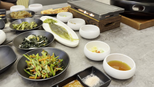 A restaurant table in Thao Dien, Saigon, featuring various Vietnamese dishes including stir-fried vegetables, a plate with a fish or seafood item, sma