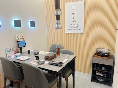 A modern restaurant interior in Thao Dien, Saigon featuring a rectangular dining table with four gray chairs, a digital display on the table, a menu b