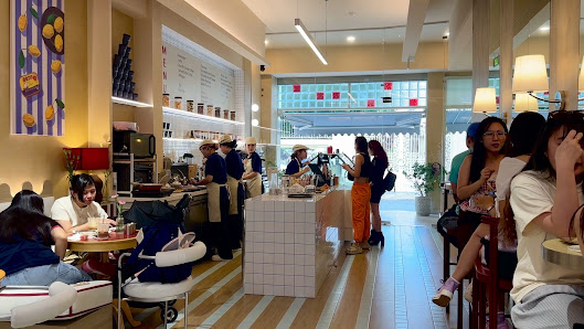 The image depicts an interior view of a modern cafe or restaurant in Thao Dien, Saigon. The space is well-lit with natural light coming through the wi