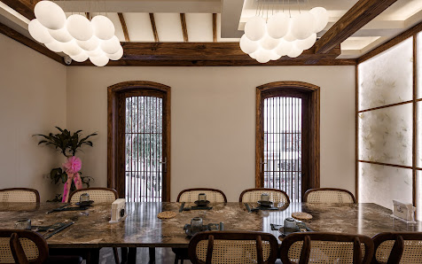 The image depicts an elegant dining room in a venue located at Thao Dien, Saigon. The space features high ceilings with exposed wooden beams and moder