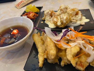 The image shows a plated dish consisting of golden-brown fried food items accompanied by shredded vegetables and two types of sauces served in small b