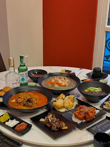 A variety of Korean dishes including a spicy soup, vegetables, and side items
