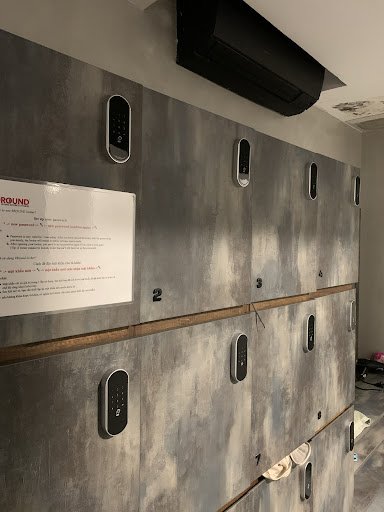 A row of modern-looking lockers in a grey metallic finish on the wall, with digital locks and numbered slots for organization.