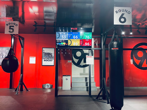 The image shows an interior view of a boxing gym or training facility in Thao Dien, Saigon. The space is characterized by red walls and black accents 