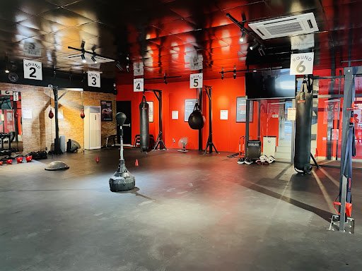 This image depicts an interior view of a gym or fitness center located in Thao Dien, Saigon. The space is spacious with red and black walls that creat