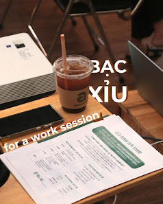 A work session setup on a desk in Thao Dien, Saigon featuring various items such as a laptop, smartphone, and documents.