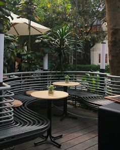 The image shows an outdoor seating area of a cafe or restaurant in Thao Dien, Saigon. The setting includes circular metal tables with wooden tops and