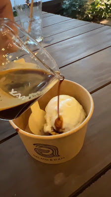 A bowl of what appears to be a dessert topped with syrup being poured from a glass container.