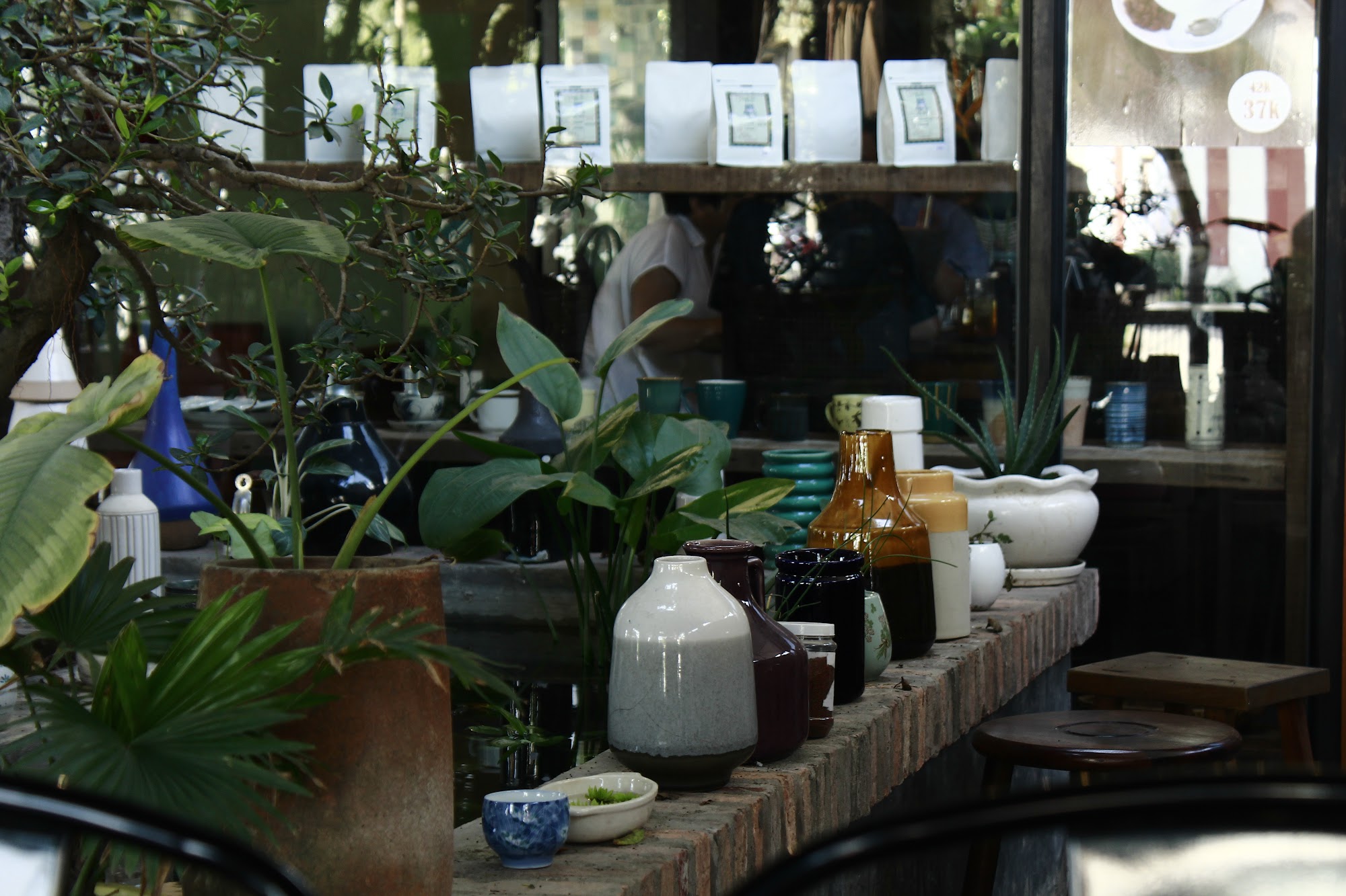 This image depicts an interior setting that appears to be a café or tea house in Thao Dien, Saigon. The scene is filled with various ceramic items and