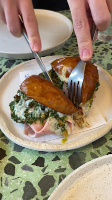 A plated dish consisting of a pastry topped with what appears to be ham and cheese on top of greens served over a bed of rice.