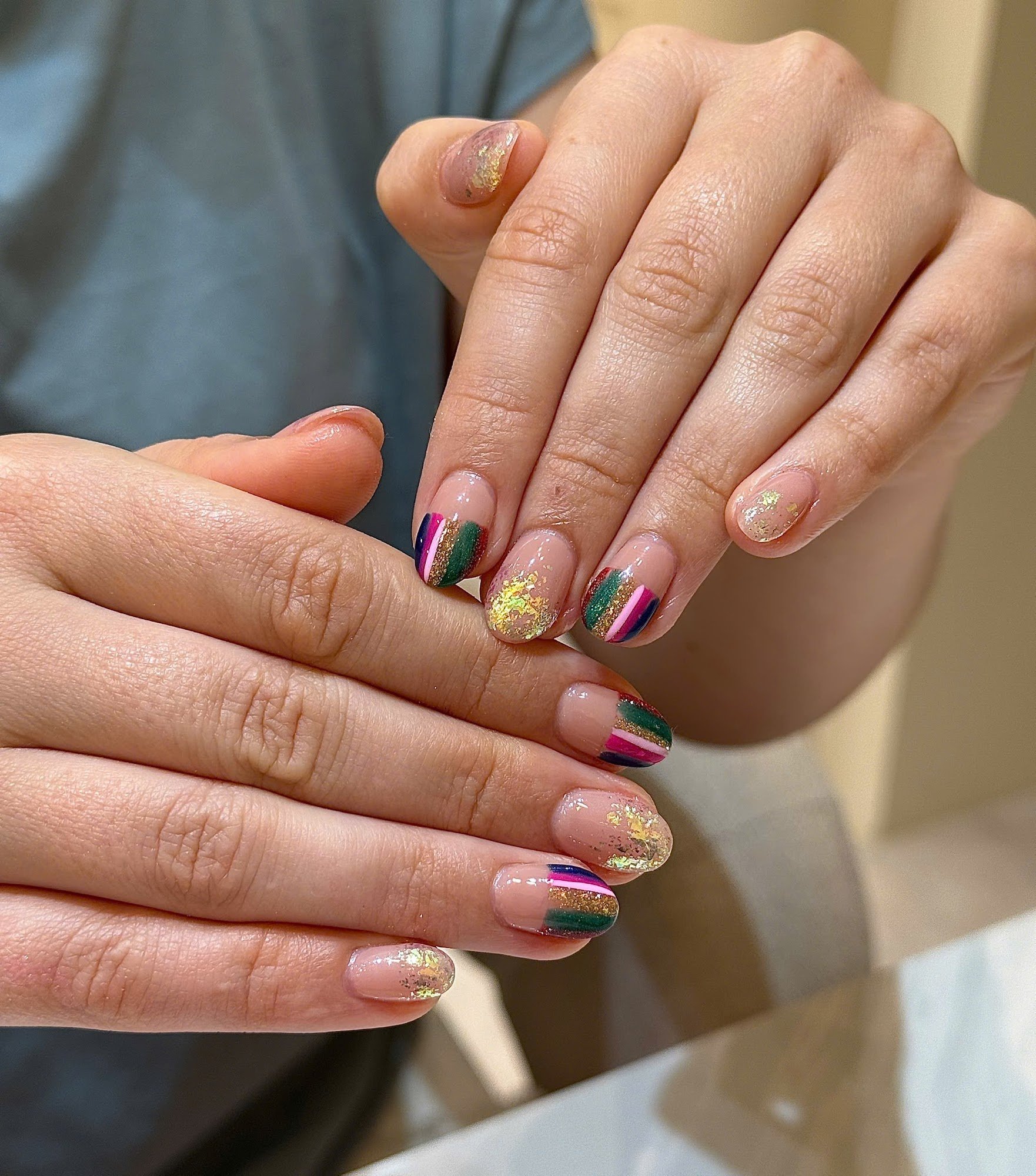 A close-up of a person's hands displaying colorful nail art against an indistinct background that suggests the interior setting, possibly in Thao Dien