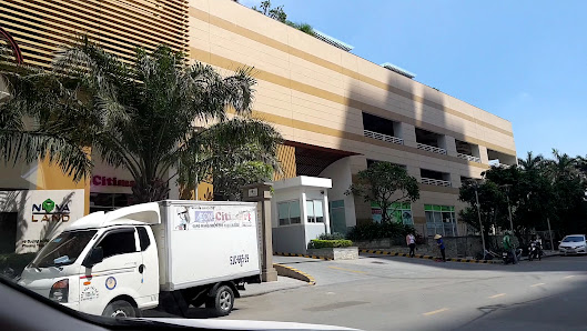 The image shows an exterior view of a commercial building with multiple floors and shops on the ground level. A white delivery truck is parked in fron