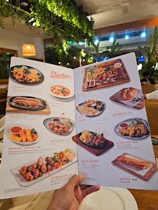A person holds an open menu showcasing multiple dishes with images and text. The menu features sections like 'Grilled' with various items including gr