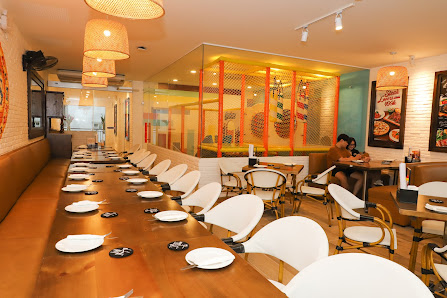 A modern restaurant interior in Thao Dien, Saigon, featuring a long wooden table with white chairs, set with plates and small black items (possibly co