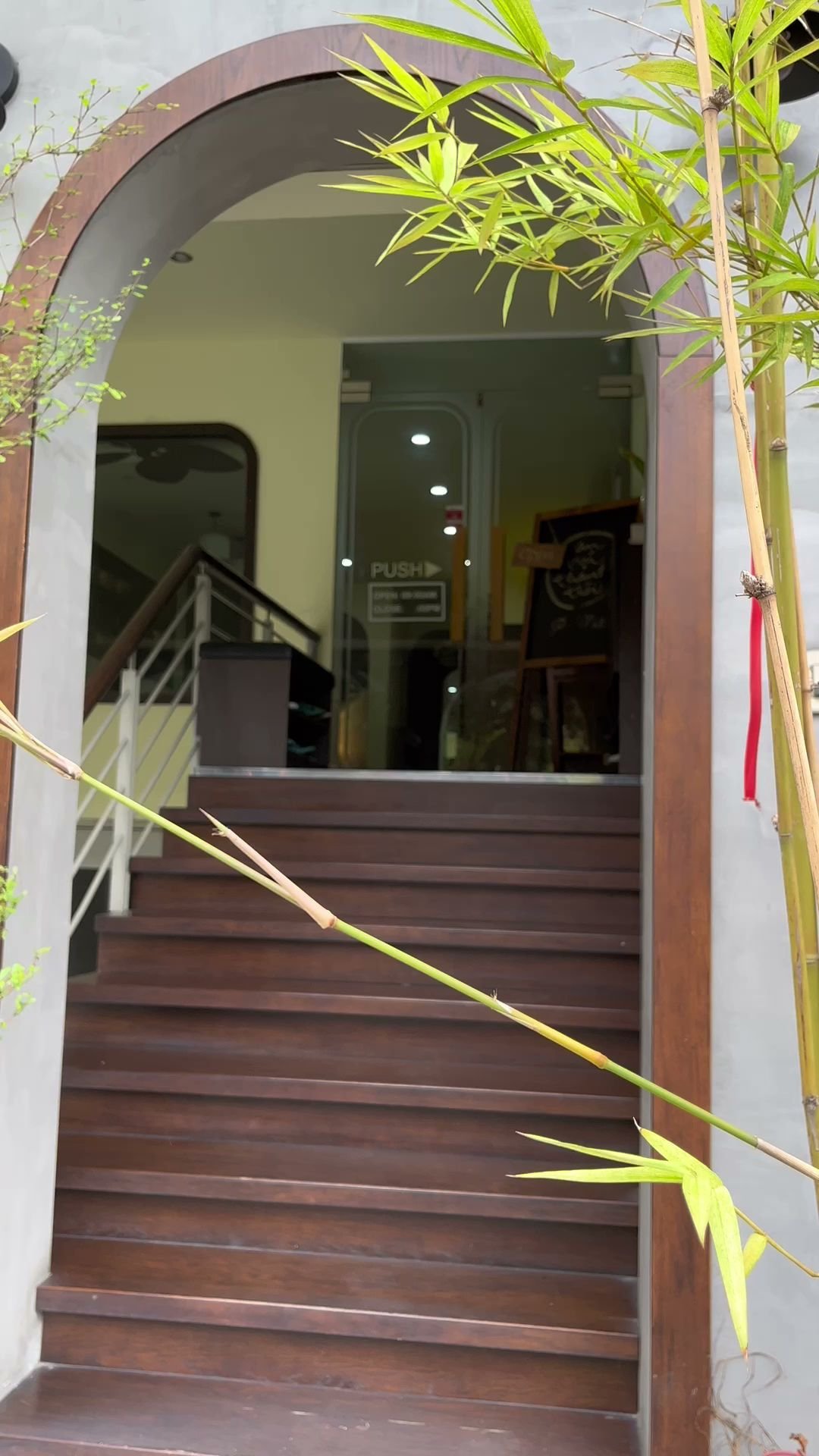 Exterior of a venue in Thao Dien, Saigon. Features a wooden staircase leading up to a glass door with 'PUSH' signage. The entrance has an arched woode