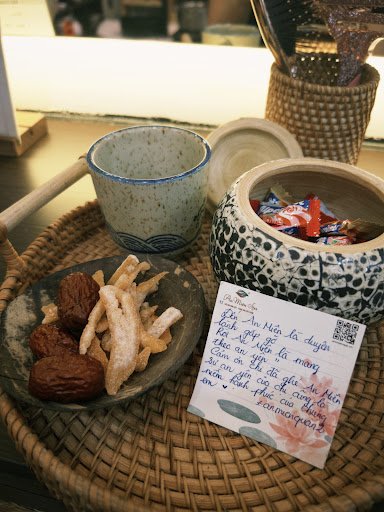 The image shows a close-up of various items on a woven tray placed on what appears to be a wooden table in an indoor setting, likely within Thao Dien,