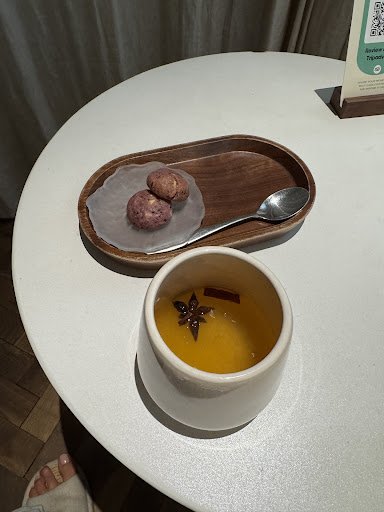 The image shows a table setting in an indoor venue named Thao Dien, Saigon with two items on display: a cup of tea or dessert drink garnished with sta