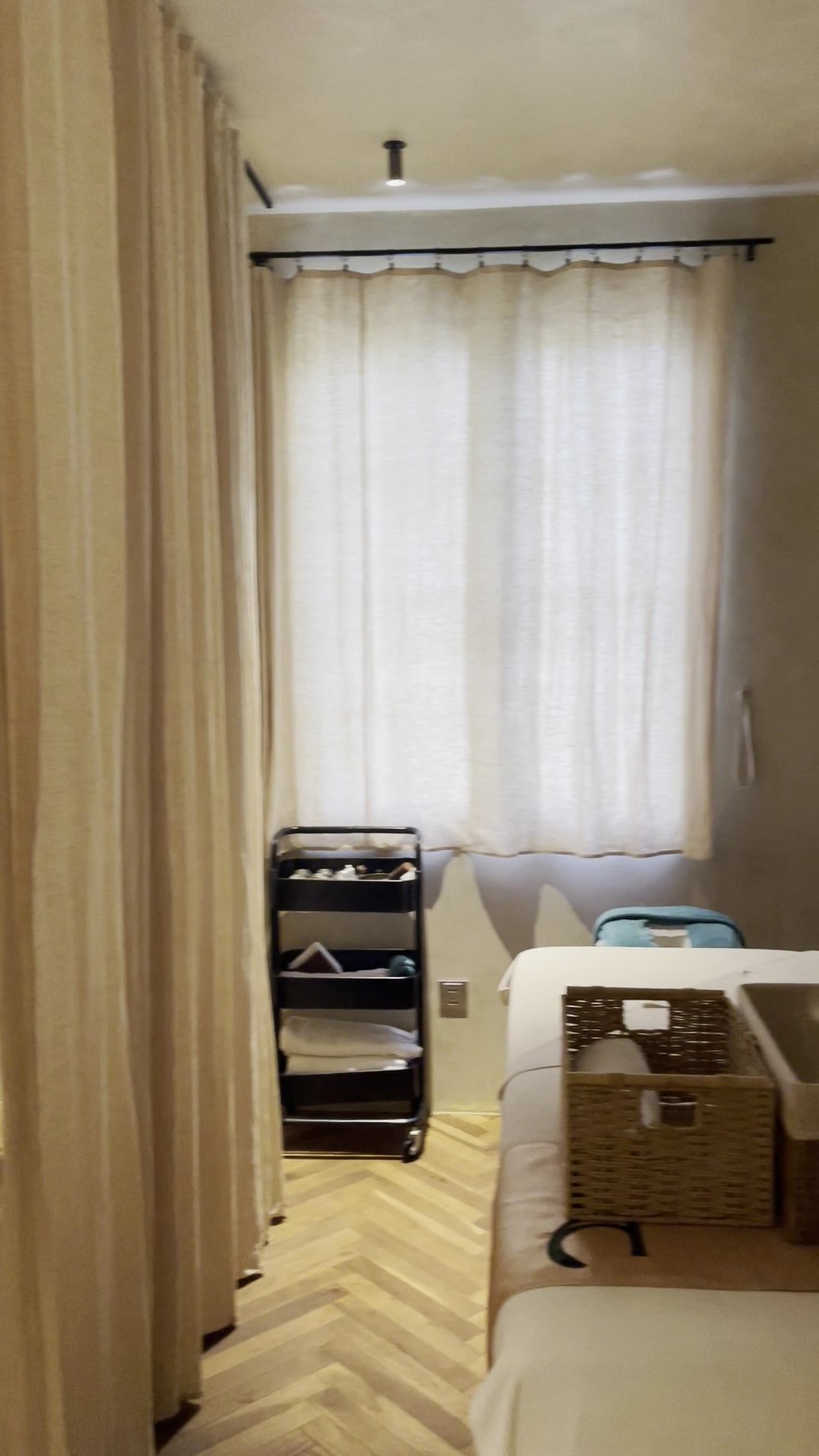 The image shows an interior room that appears to be part of a spa or salon setting. The focus is on the corner where two massage beds are placed, with