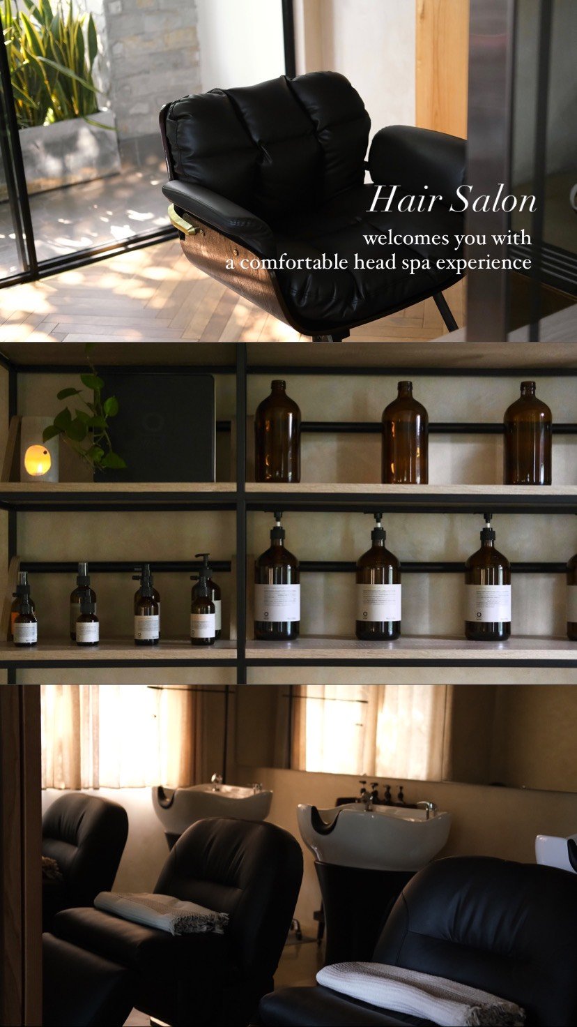 The image depicts a modern and stylish hair salon interior featuring black leather reclining chairs for clients to relax in while receiving services, 