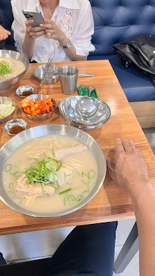 A group of people are seated around a table in what appears to be an indoor dining setting at Thao Dien, Saigon. The focus is on the large metal bowl 