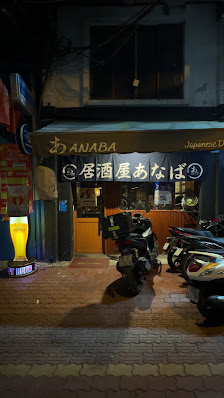 The image shows an exterior view of a Japanese restaurant named 'ANABA' at night time in Thao Dien, Saigon.