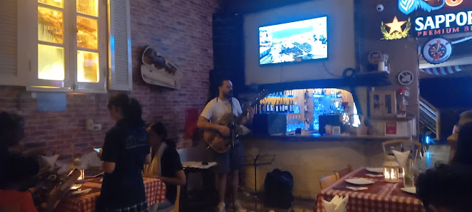 The image depicts an indoor setting of a casual dining establishment where patrons are seated at tables with red and white checkered tablecloths, enjo