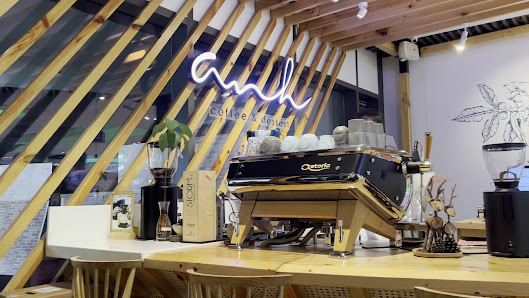 The image shows an interior view of a modern coffee shop named 'Cafe & Deli'. The space features wooden slatted walls and ceiling, with large windows