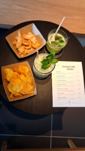 The image shows a round table on which there are two plates of food and two drinks accompanied by a menu card.