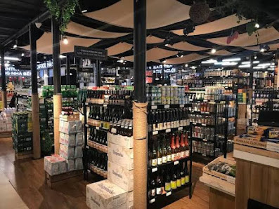 The image depicts the interior of a retail store in Thao Dien, Saigon, featuring multiple shelves stocked with various bottles (likely alcoholic bever