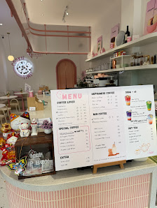 The image shows an interior view of a cafe or restaurant in Thao Dien, Saigon with a pink and white color scheme on the counter area where a menu boar