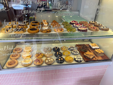 A display case in a bakery or café showcasing an assortment of pastries and desserts on two shelves.