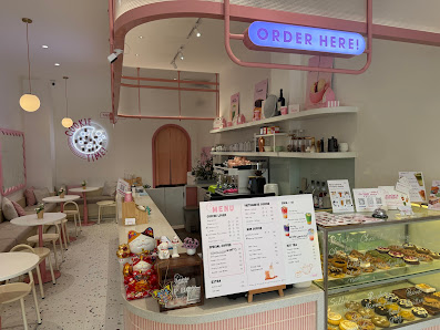 The image shows an interior view of a modern cafe or dessert shop in Thao Dien, Saigon. The decor includes pastel colors with pink and white tones dom