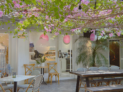 The image shows an interior view of a cafe or boutique located in Thao Dien, Saigon. The space is decorated with pink and green floral elements hangin
