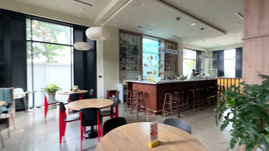 The image shows an interior view of a modern café or bar located in Thao Dien, Saigon. The space is well-lit with natural light coming through large w