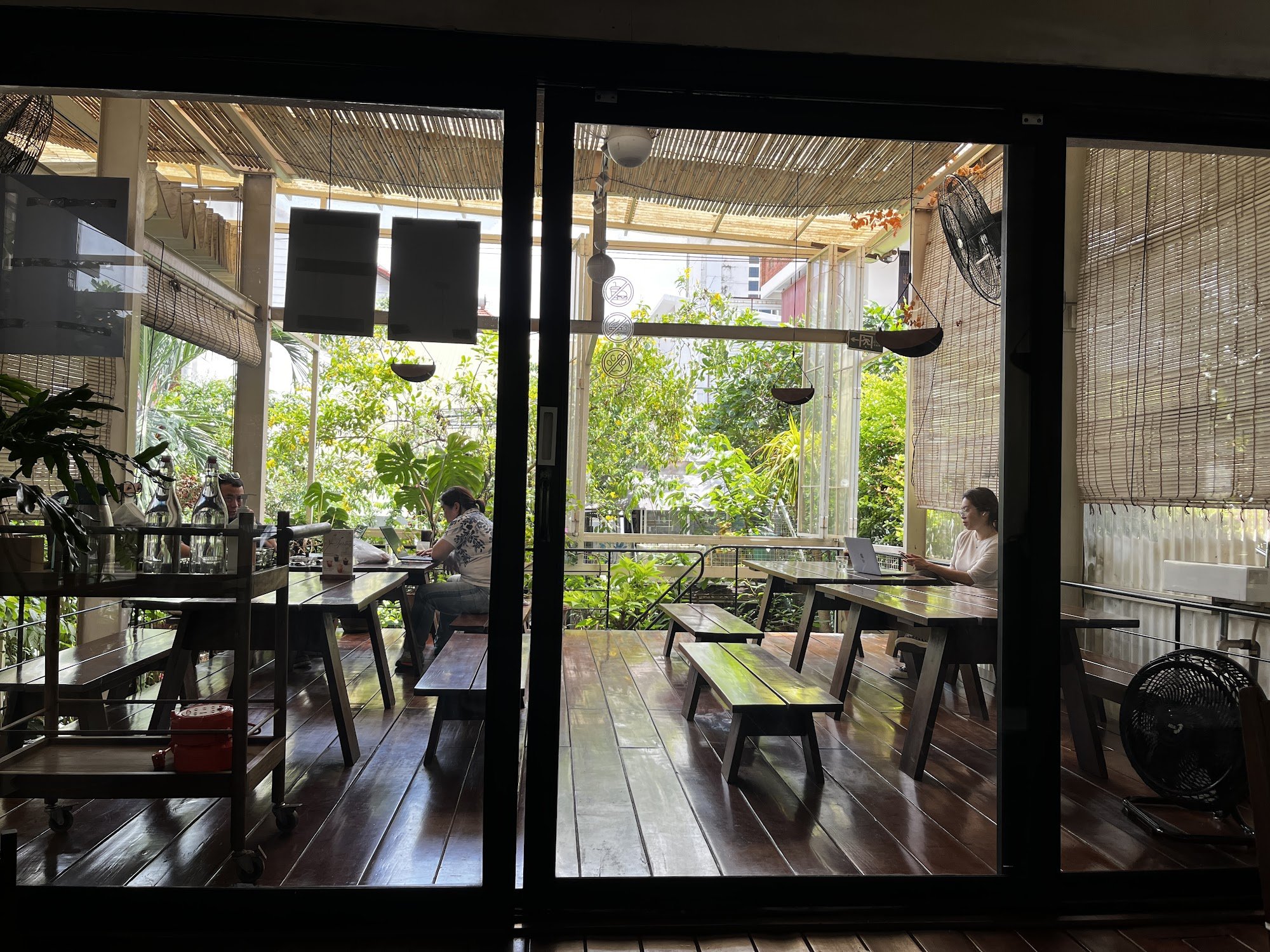 The image shows an interior view of a cafe or restaurant in Thao Dien, Saigon. The space is well-lit with natural light coming through the large glass