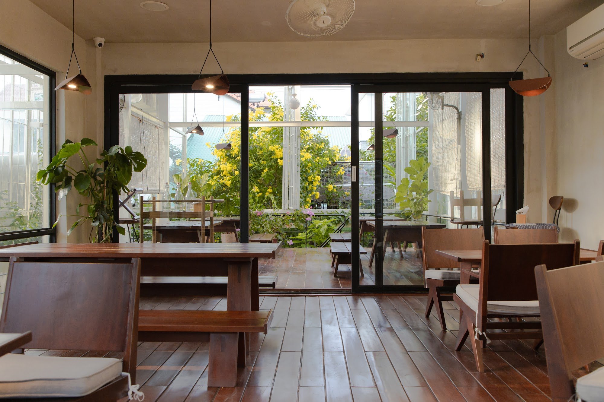This image depicts an interior view of a cafe or restaurant in Thao Dien, Saigon. The space features wooden flooring and furniture with modern design 