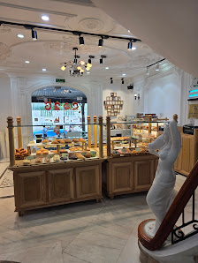 The image shows an interior view of a well-lit buffet area in Thao Dien, Saigon with various food items displayed on wooden counters and shelves.