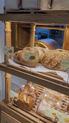 The image shows a display case in Thao Dien, Saigon filled with various types of bread and pastries on wooden shelves.