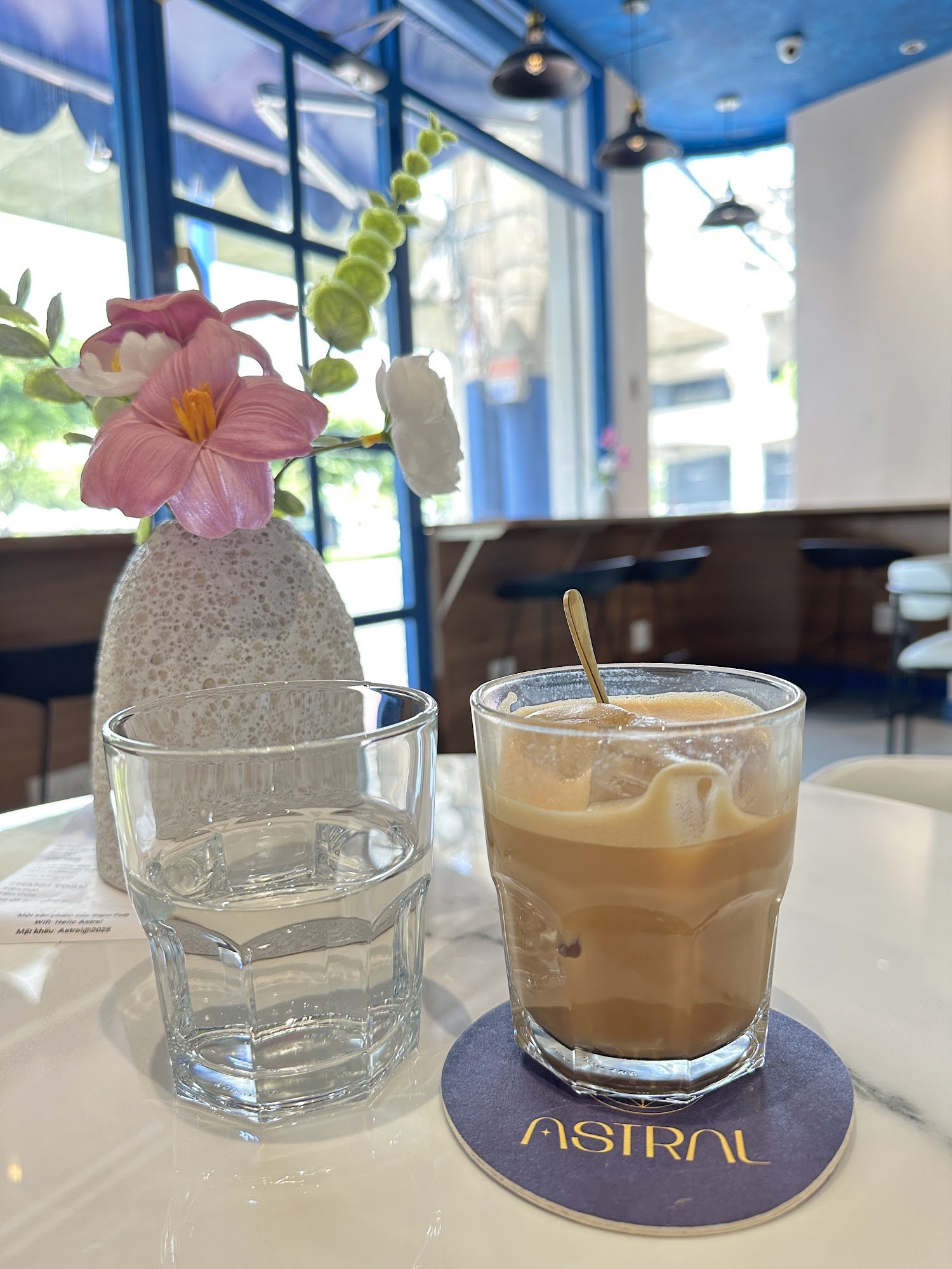 A well-lit interior of a cafe featuring modern decor and natural light streaming in through large windows.