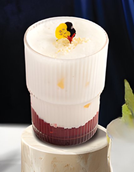 A layered dessert in a tall glass container featuring white and red layers topped with what appears to be a small figurine of two characters embracing