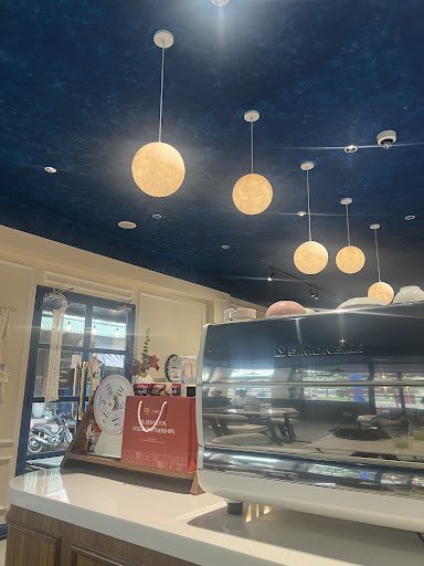 The image shows an interior view of a modern café or restaurant named 'Starbucks'. The ceiling is adorned with spherical pendant lights, and the count