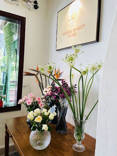The image shows an interior setting of a place named 'Nature Beauty Home', which appears to be decorated with various flower arrangements in vases on