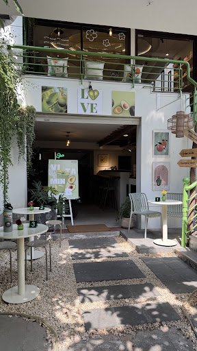 The image shows an exterior view of a cafe named 'LOVE' located in Thao Dien, Saigon. The entrance is open with greenery and plants adorning the area