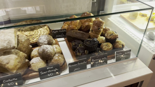 A display case in a bakery or café showcasing an assortment of baked goods such as pastries and muffins with clear labels indicating their names, pric