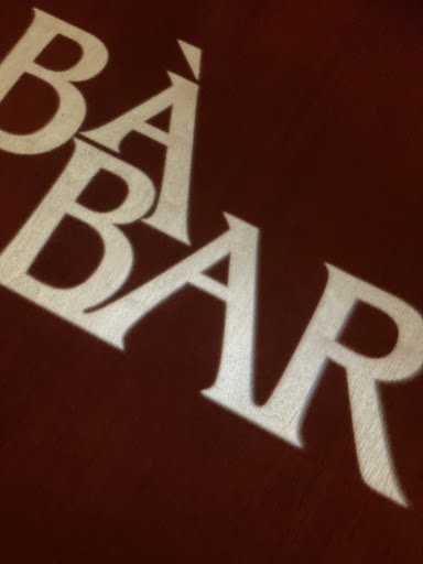 The image shows a close-up of the text 'BÀ BÁ BAR' on what appears to be a maroon background, possibly part of an interior decor element such as a wal