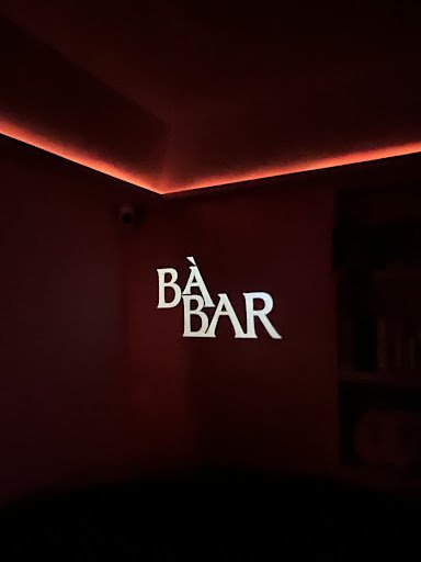 The image shows a dimly lit interior corner of what appears to be a bar or lounge area with the word 'BAR' prominently displayed in white letters on a