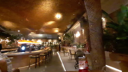 The image depicts the interior of a venue in Thao Dien, Saigon. It features a bar area with high stools, multiple dining tables with chairs, a texture